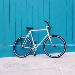 white road bike leaning on teal wooden wall during daytime